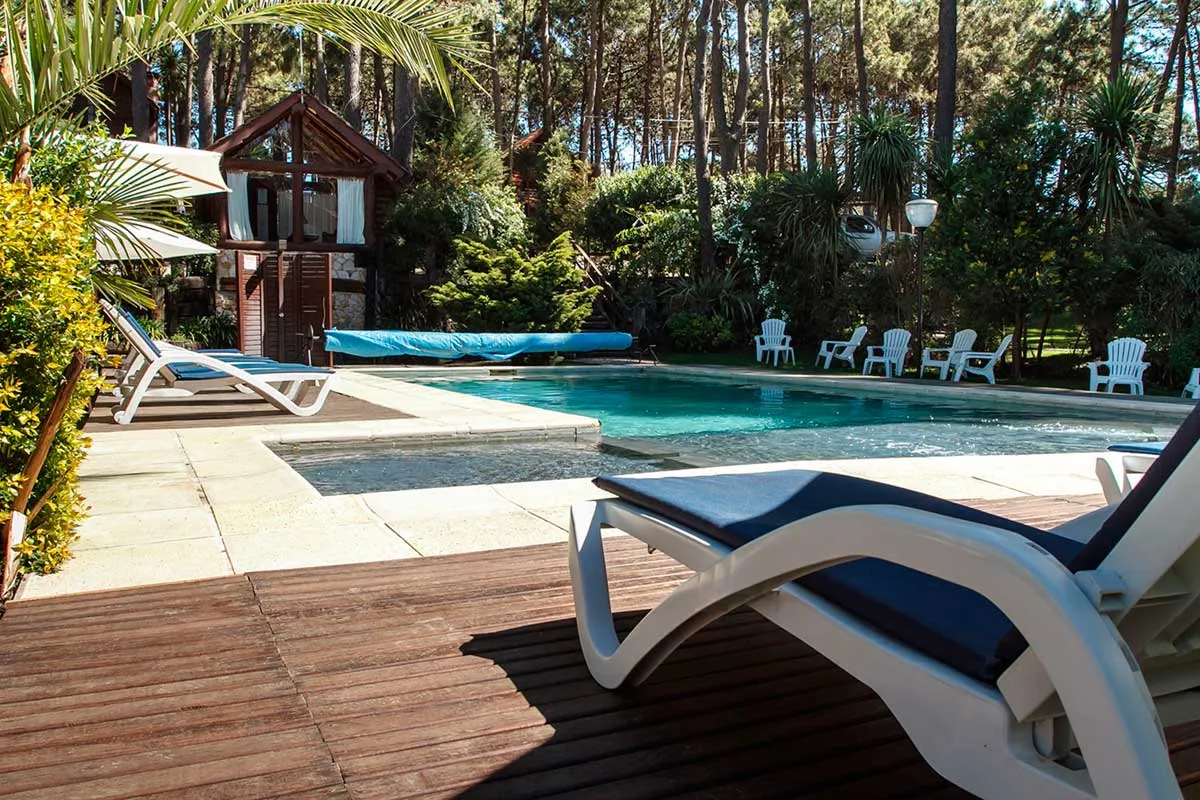 Vista lateral de la piscina con deck de madera y reposeras.