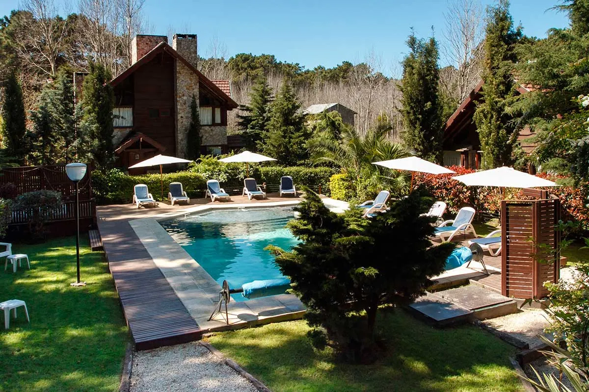 Vista panorámica del sector piscina rodeado de verde y cabañas.