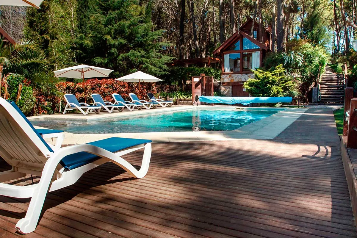 Piscina principal con reposeras y sombrillas entre el bosque.